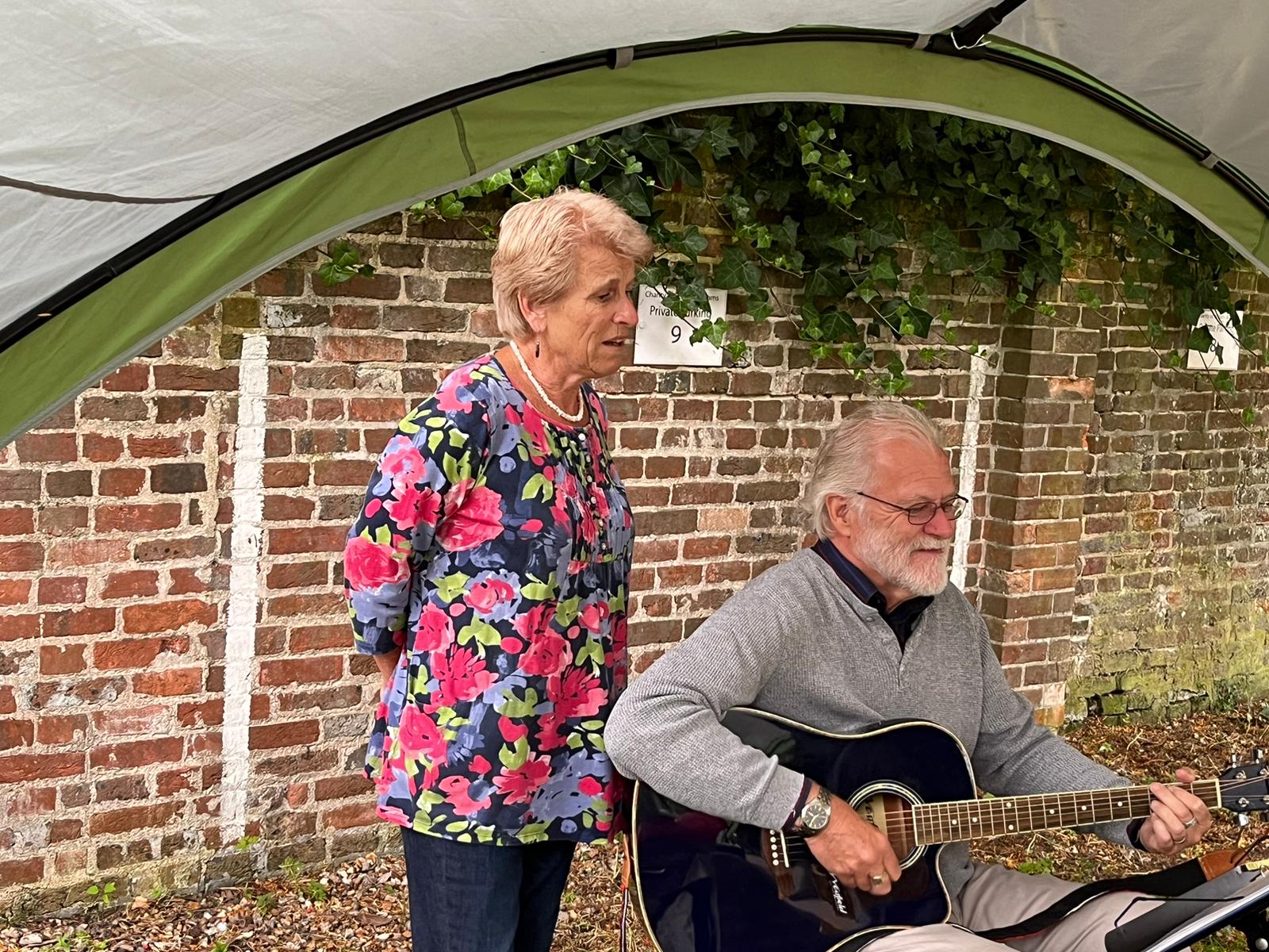 Clara and Colin singing in the rain at June's Last Friday social event